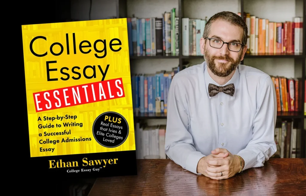 A man with glasses and a bow tie sits at a table in front of bookshelves. Next to him is the cover of the book "College Essay Essentials" by Ethan Sawyer.