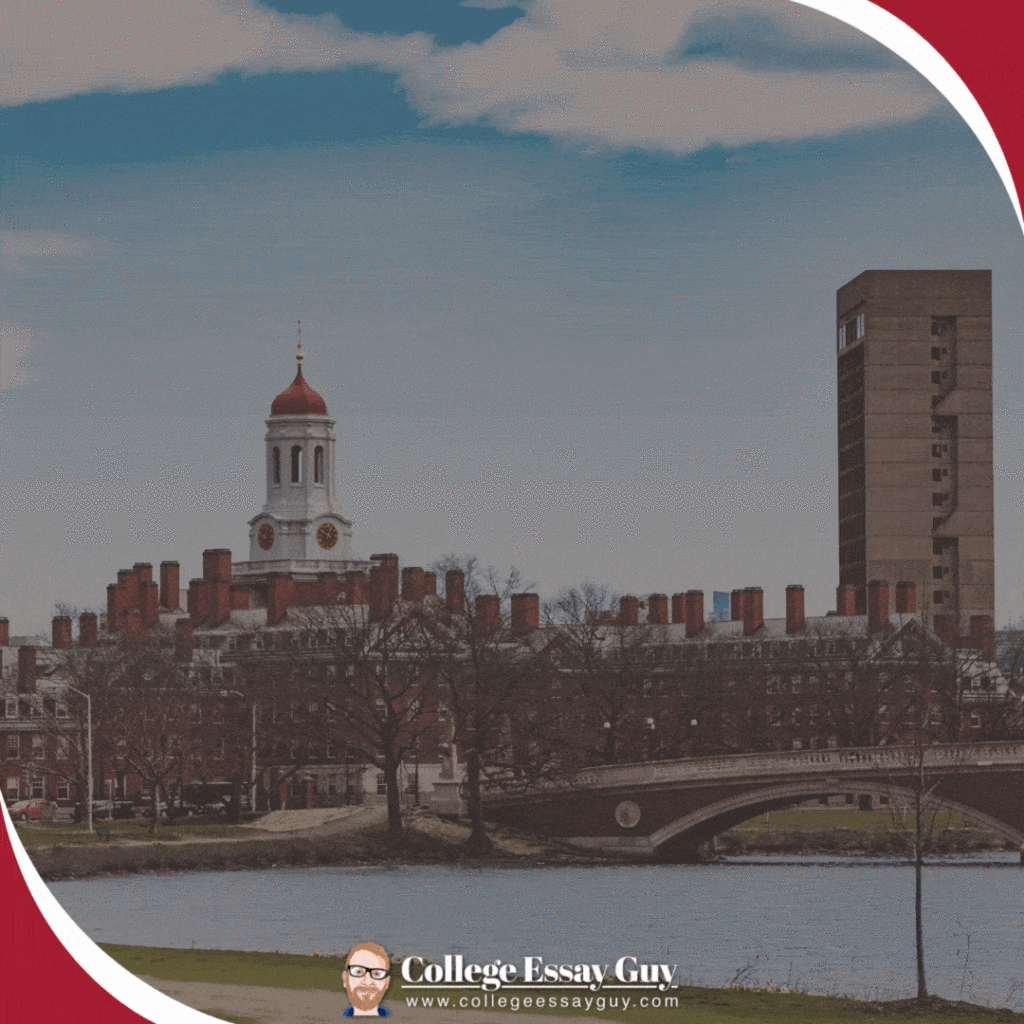 View of Harvard University campus with the iconic red-capped clock tower, brick buildings, and a river in the foreground under a blue sky.