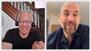 Two men are having a video call; one is wearing glasses and a headset, and the other is smiling with a trimmed beard.