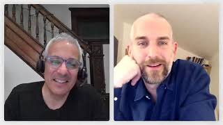 Two men are having a video call; one is smiling and wearing headphones, while the other is resting his chin on his hand and looking at the camera.
