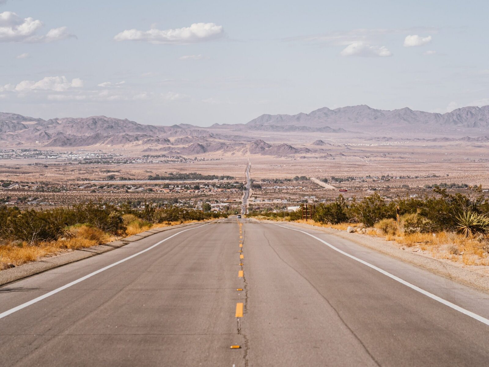 gray_concrete_road_near_green_grass_field_under_white_clouds-scopio-03456e37-a2ae-430d-8af6-ea1e7f2f73c8.jpg